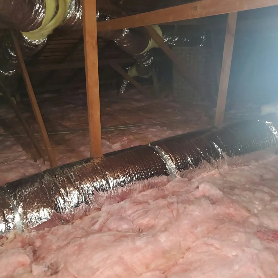 New attic insulation fitted tight around flex ductwork