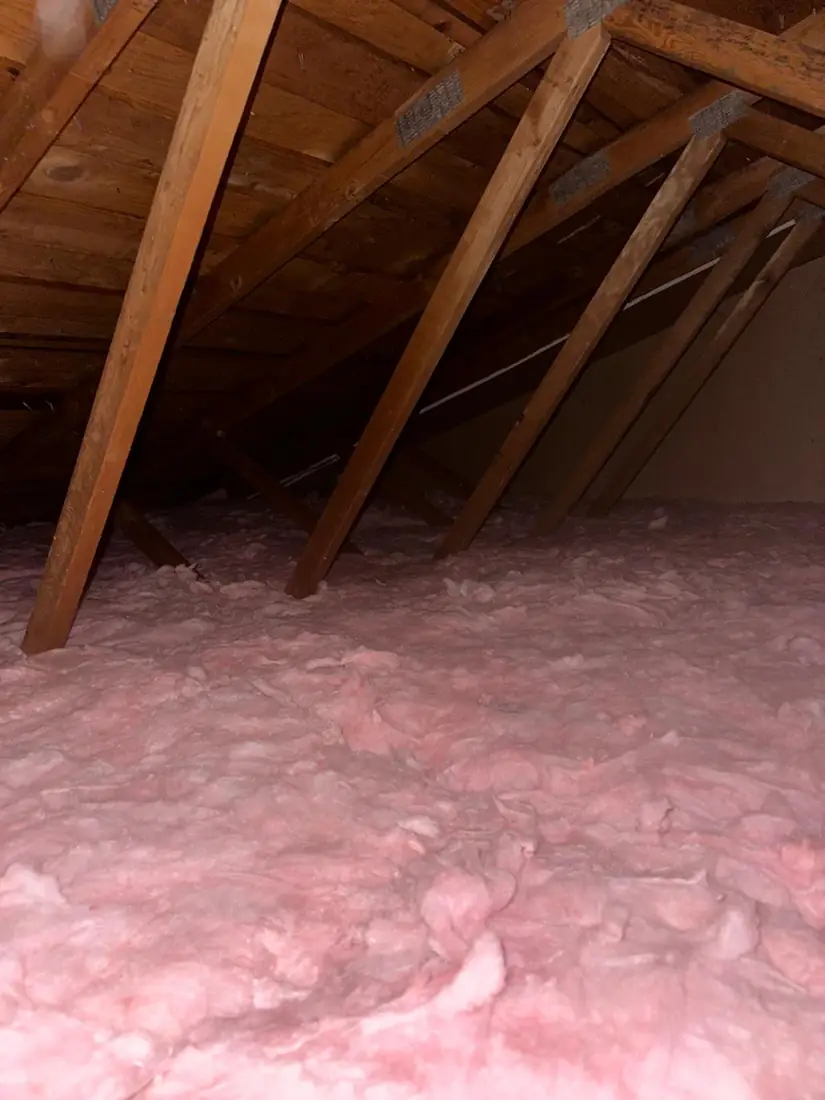 Finished attic with a full, even layer of new fiberglass insulation