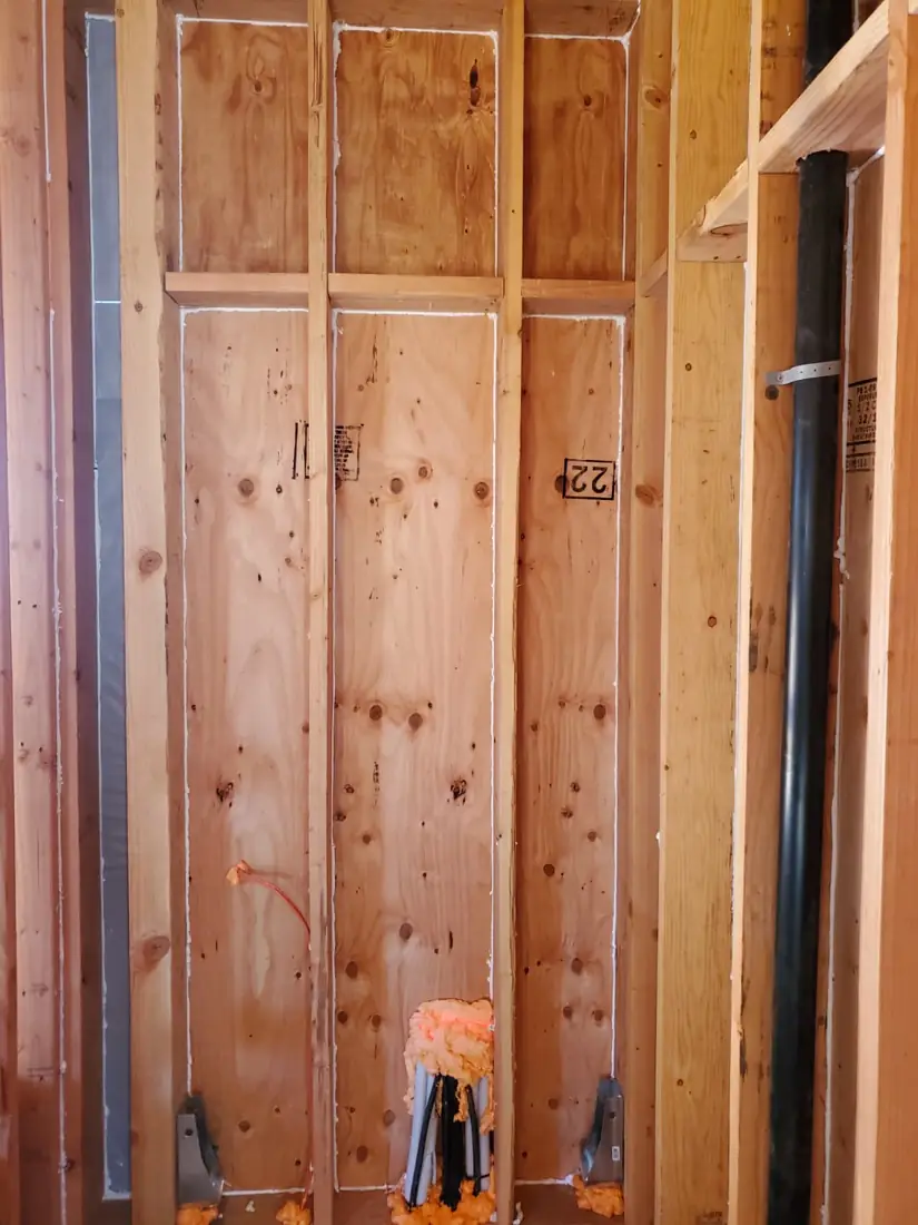 Open wall framing with empty stud bays before insulation
